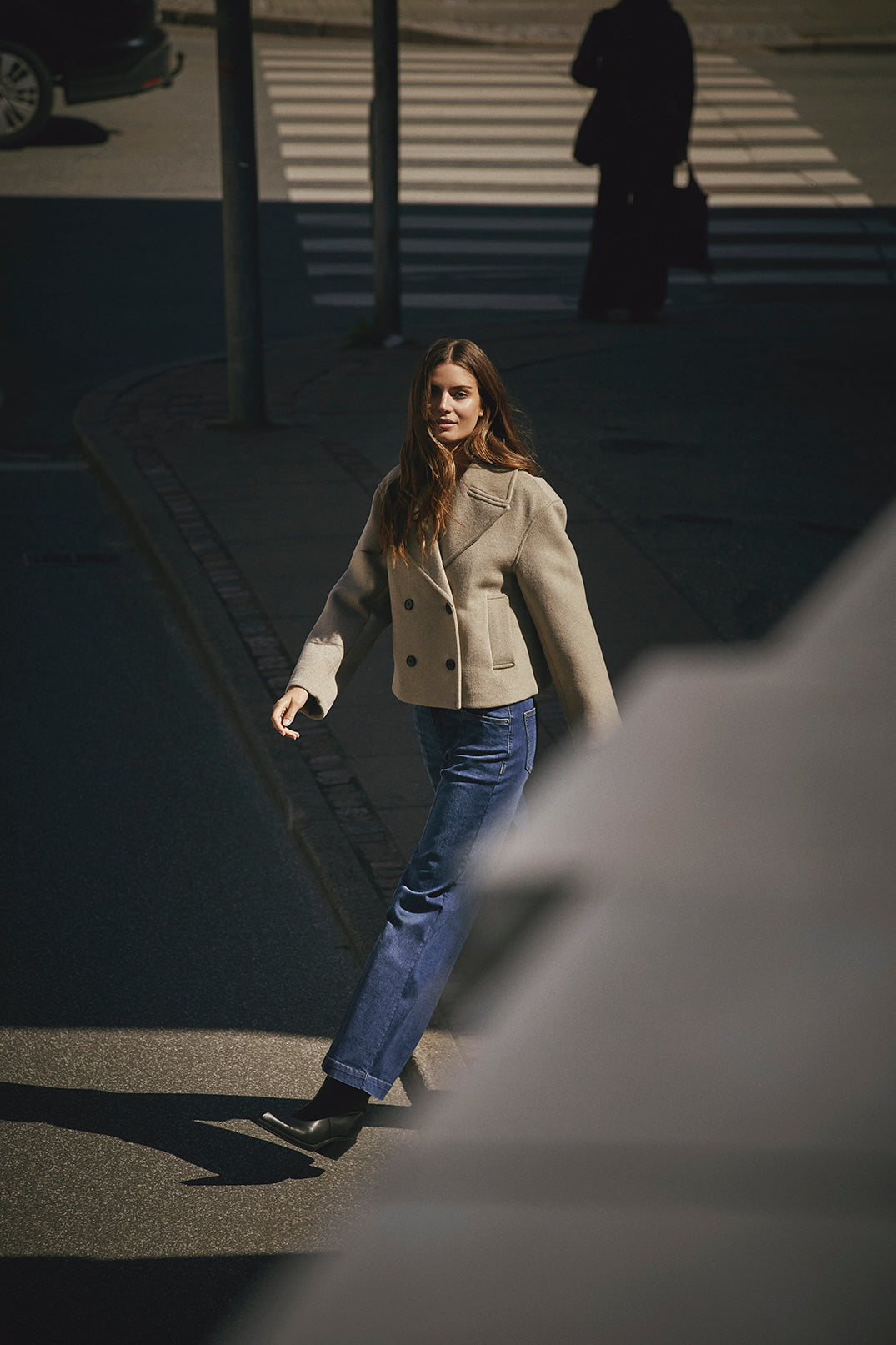 Woman walking on a city street with a blurred foreground